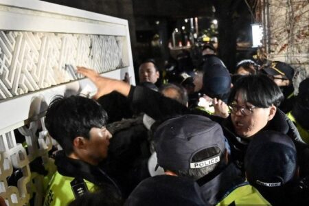 Polisi menahan massa yang memaksa masuk gedung Majelis Nasional di Seoul, Korea Selatan, Selasa (3/12/2024), setelah Presiden Yoon Suk Yeol mengumumkan darurat militer.(AFP/JUNG YEON-JE)